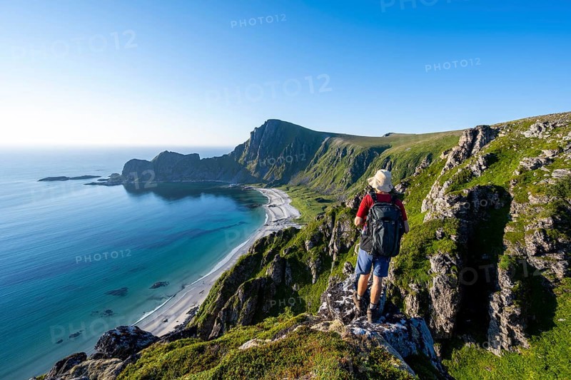 Mountaineer in front of view of coastal landscape, steep coast with summit Måtind or Måtinden, Høyvika beach and sea, hike to the summit of Måtind, Andøya island, Vesterålen, Nordland, Norway, Europe