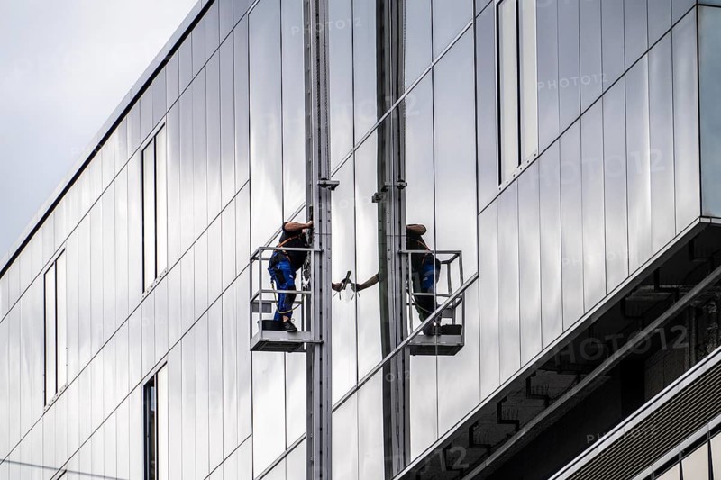 Window cleaner, facade cleaning, window cleaning, on a glass facade in Düsseldorf, ladder cage from the roof