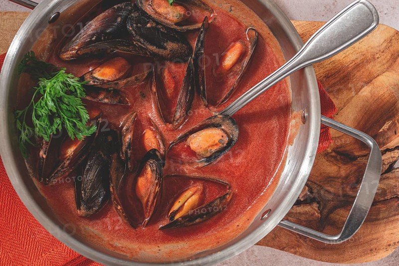 Mussels in tomato sauce, in a silver dish, on a wooden board, rustic style, no people, top view