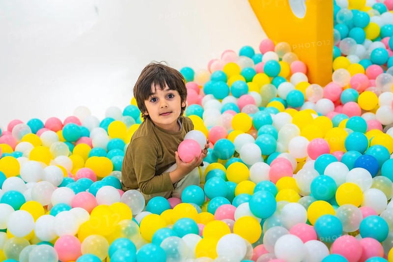 Young boy enjoying playtime in a vibrant ball pit, surrounded by colorful plastic balls in a lively indoor play area