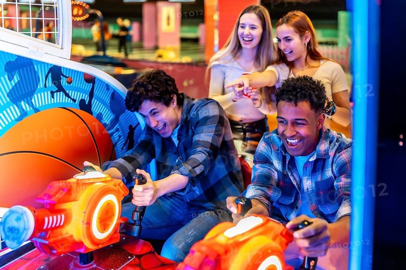 Young adults enjoying time together while playing arcade games in a vibrant bowling alley, filled with laughter and excitement