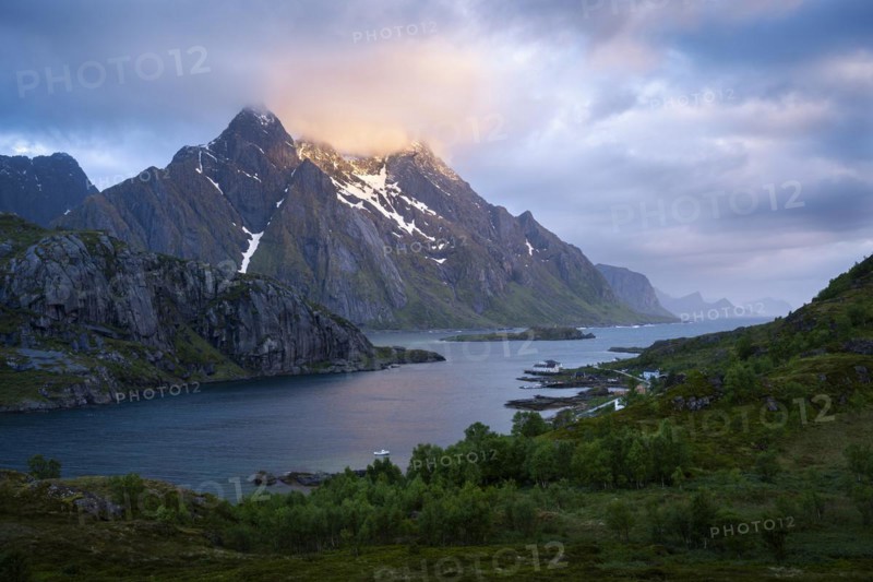 Mountain landscape on the Lofoten Islands. View across the Maervollspollen fjord to mountains in the night sunlight. At night at the time of the midnight sun, clouds and sun. Early summer. Vestvagoya, Lofoten, Norway, Europe
