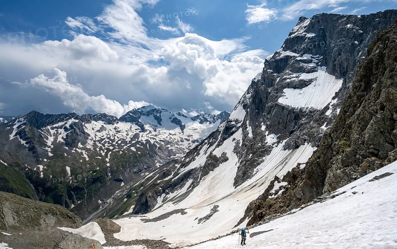 Mountaineer hiking in a snowfield, Nördliche Mörchnerscharte, behind mountain peak Kleiner Mörchner and Greizer Spitze with snow, Berliner Höhenweg, Zillertal Alps, Tyrol, Austria, Europe