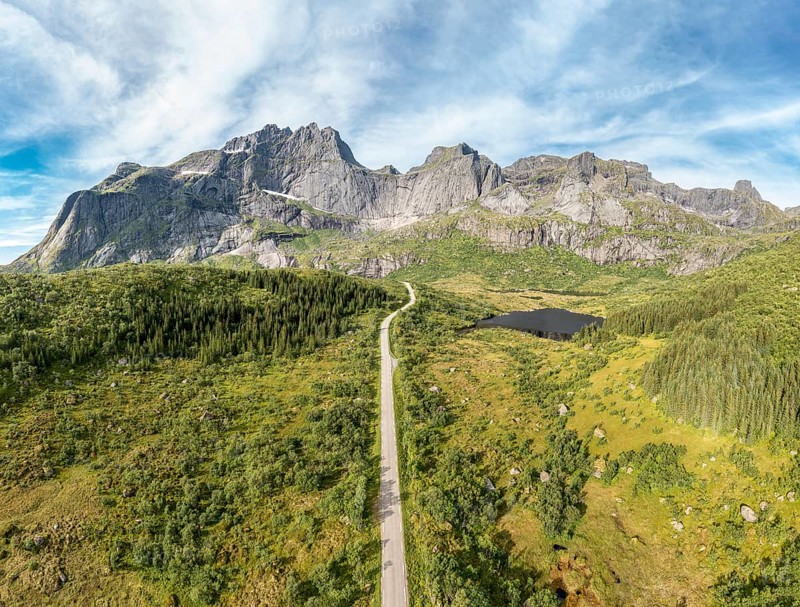 Panoramic aerial view of road in mountain scenery, passing lakes and meadows, road from E10 to village Nusfjord, Lofoten, Norway, Europe