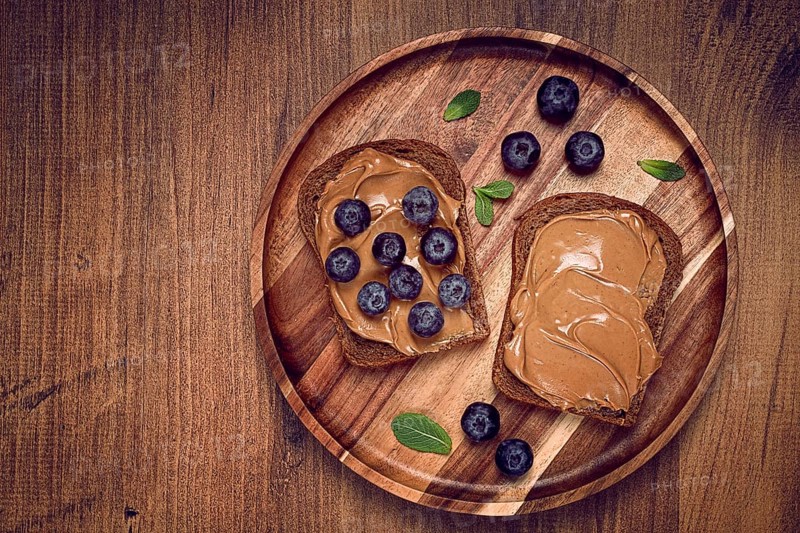 Rye bread with peanut paste and fresh blueberries, top view, no people