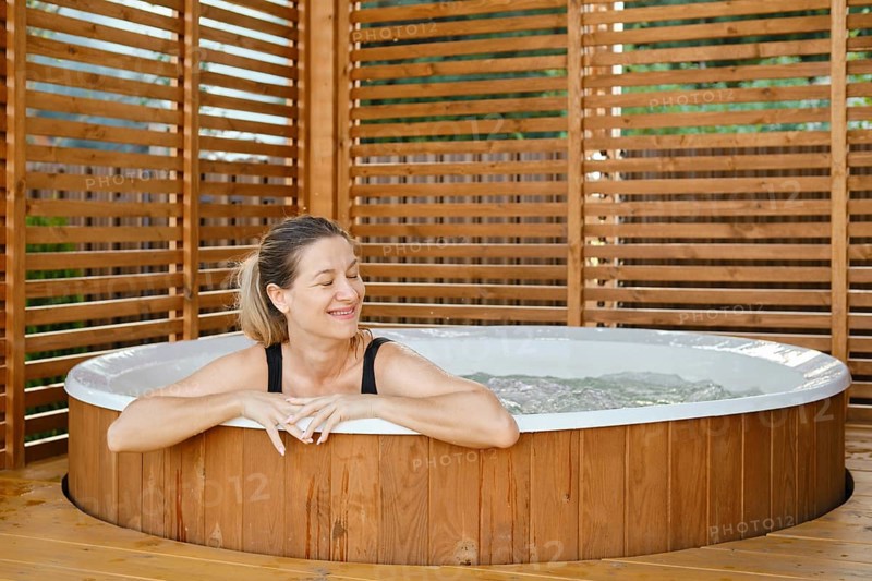 Portrait of carefree happy smiling woman relaxing at outdoor hot tub during her vacation
