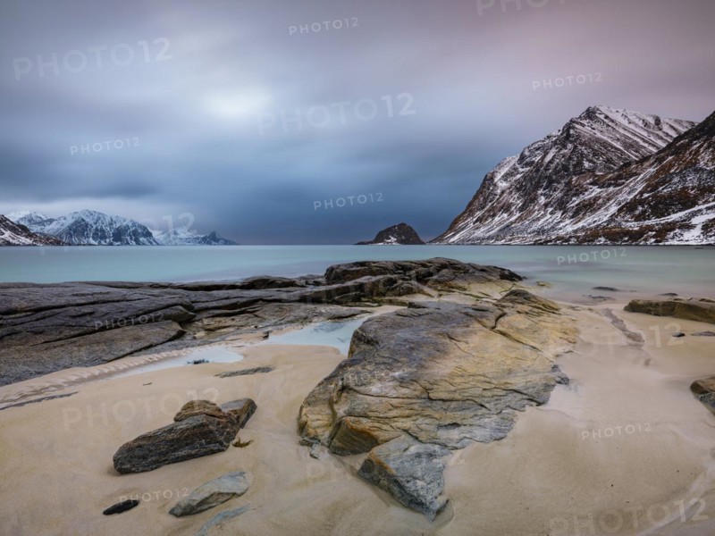Rocks on Haukland beach, snow-capped mountains in the background, Vestvågøya, Lofoten, Norway, Europe