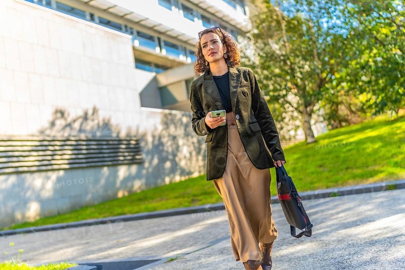 Full length photo of a beauty Arab businesswoman in casual modest clothes walking along the city