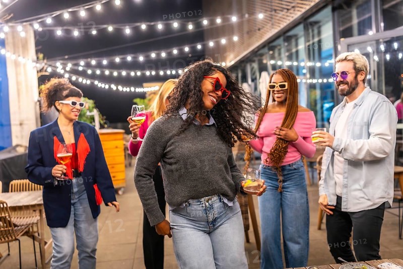 Energetic latina woman dancing with friends at night party in a roof of a bar at city