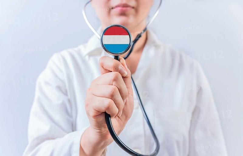 Female doctor holding stethoscope with Luxembourg flag. National health system of Luxembourg