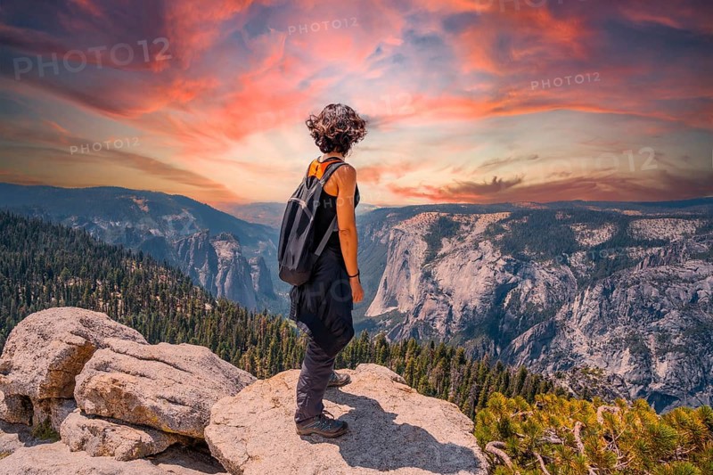 A young woman trekking at Sentinel Dome Lookout in Yosemite National Park looking at El Capitan Mountain. United States