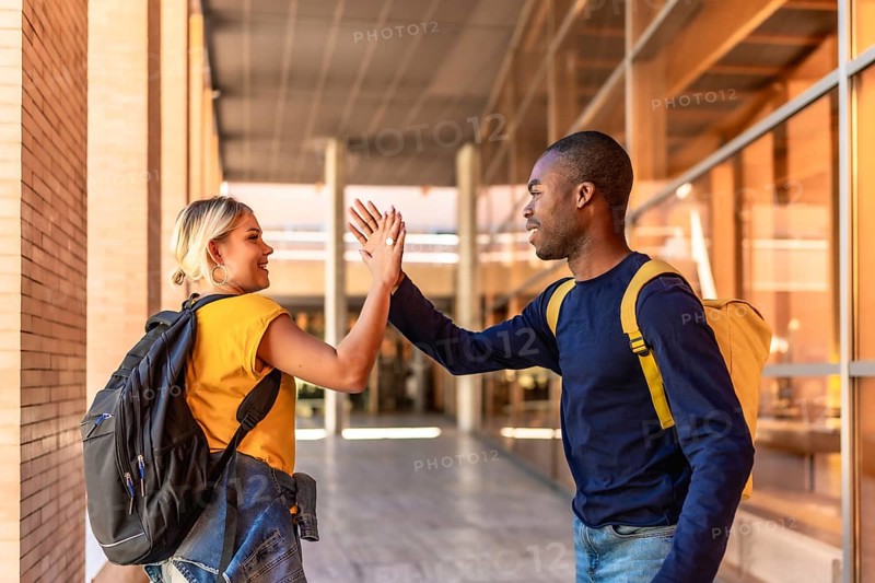 Multi-ethnic caucasian female and african male students high-fiving at the university