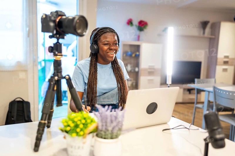 Young female content creator smiling and recording video with professional equipment in her living room