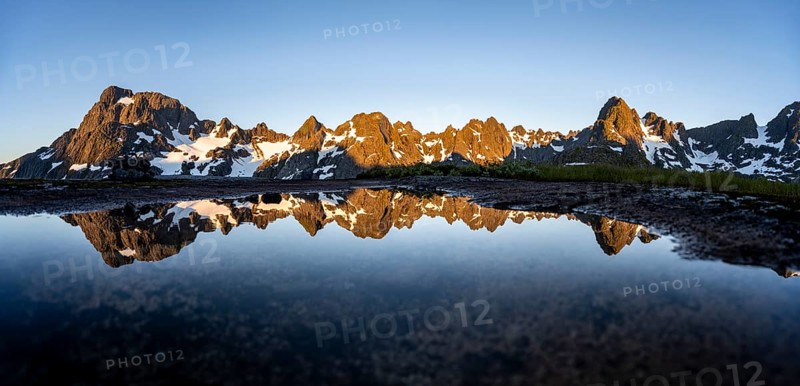 Rocky mountain peaks reflected in a small pond, mountain landscape with alpenglow at sunrise, at the Trollfjord Hytta, at the Trollfjord, Lofoten and Vesterålen, Nordland, Norway, Europe