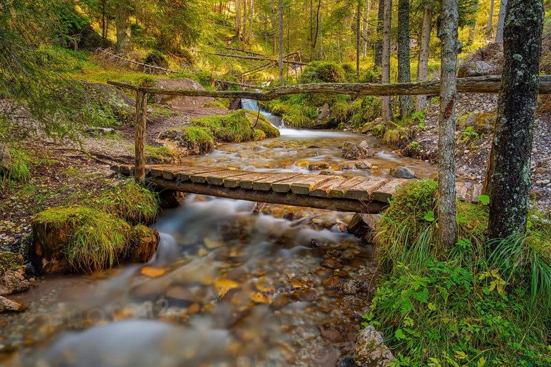 View of a rustic wooden bridge leading over a torrent, long exposure, Dolomites, Puez-Geisler nature park Park, St. Magdalena, Funes, Villnöss Valley, South Tyrol, Italy, Europe