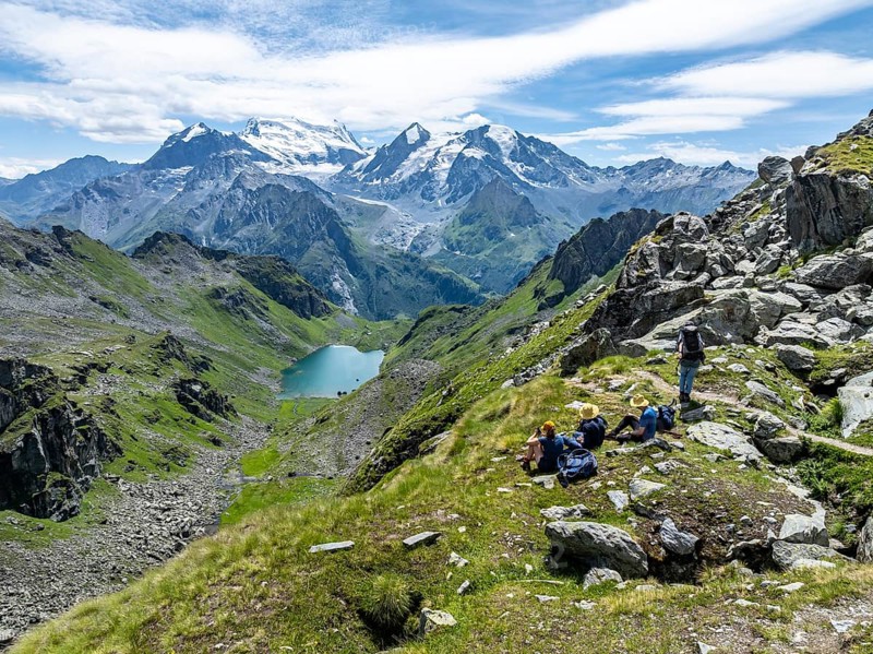 Hikers taking a break, mountain lake Lac de Louvie with glaciated summit of the Grand Combin, Val de Bagnes, Valais, Switzerland, Europe