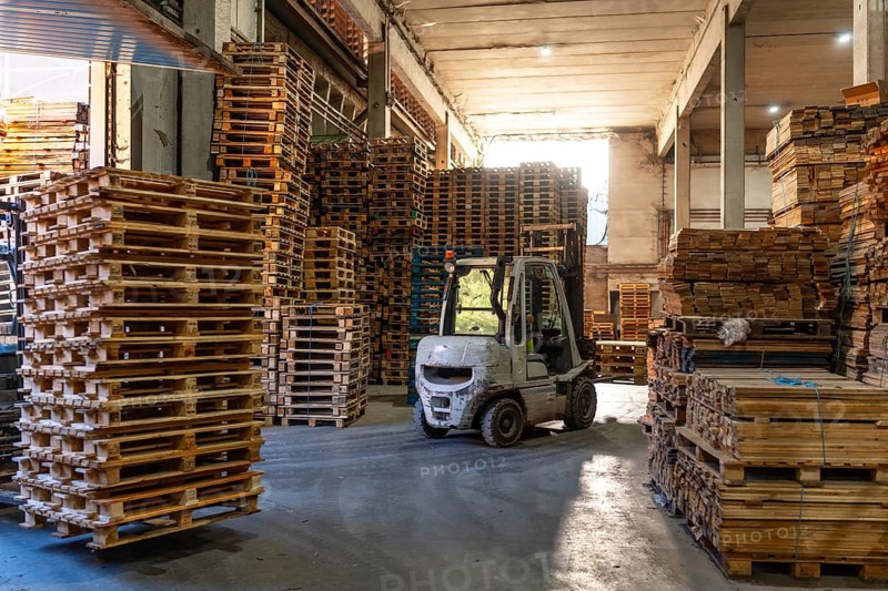 Full length photo with no people of a forklift in a pallet storage room in a recycling plant