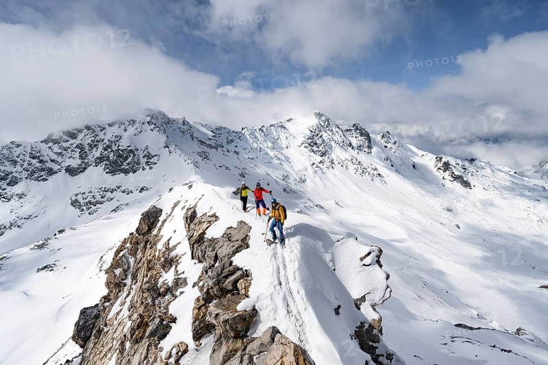 Three mountaineers climbing the narrow ridge of Piz Laviner, view of mountain panorama in winter mountain landscape, Grisons Haute Route, Albula Alps, Rhaetian Alps, Grisons, Eastern Switzerland, Switzerland, Europe