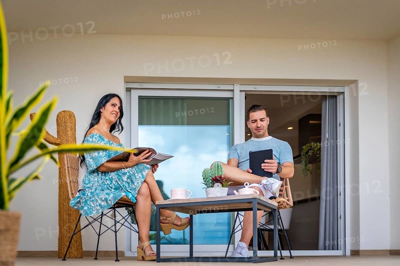 Daydreaming of a couple reading and using tablet drinking coffee in the patio