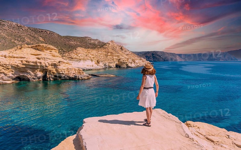 A young woman in a white dress looking at the sea in Rodalquilar in Cabo de Gata on a beautiful summer day, Almería. Mediterranean sea, spain