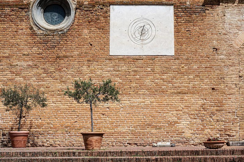 Brick wall with a sundial and two olive trees in a pot on a Mediterranean site, Tuscany, Italy, Europe