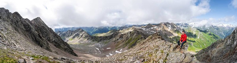 Panorama, mountaineer sitting on a rock, on a steep rocky ridge, on the summit of the Lasörling, view of the mountain panorama of the Venediger group, Lasörling group, Hohe Tauern National Park, East Tyrol, Tyrol, Austria, Europe