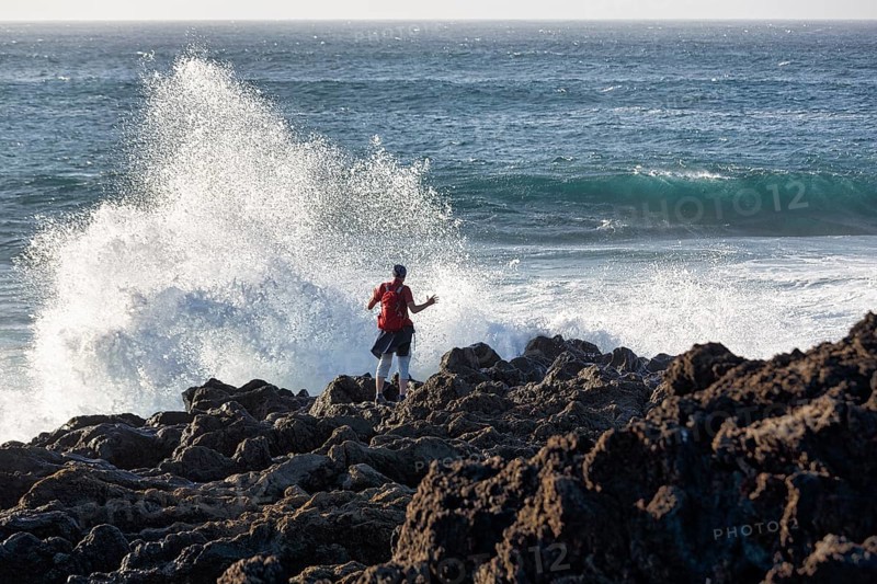 Rocky west coast, black lava coast, coastline, hiker looking at the surf, El Golfo, Yaiza, Lanzarote, Spain, Europe