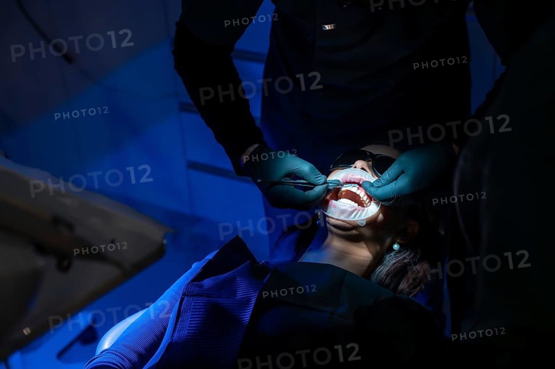 Dentist applying whitening gel on patient's teeth, enhancing oral health and creating a radiant, confident smile in a modern dental clinic