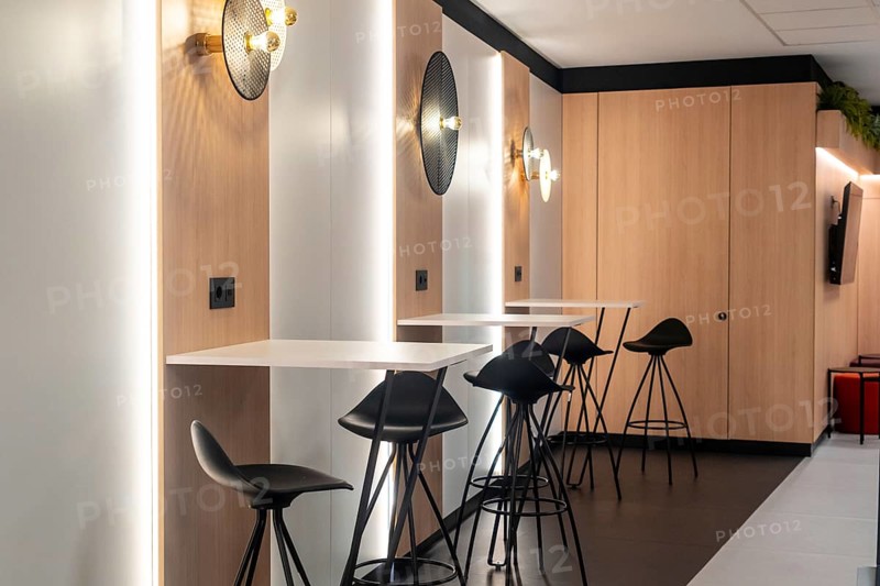 Modern airport workspace offering travelers a stylish area to work or relax, featuring sleek tables, comfortable bar stools, and power outlets
