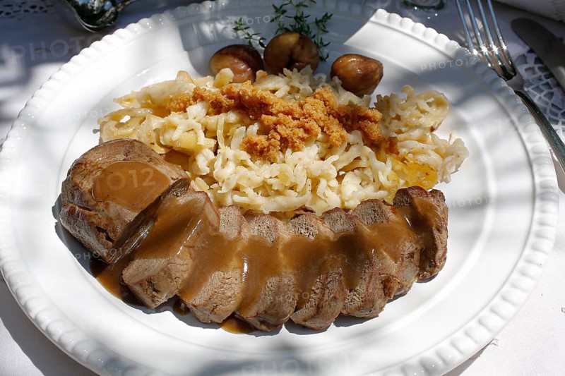 Swabian cuisine, roast venison with spaetzle, chestnuts and breadcrumbs, breadcrumbs, saddle of venison arranged on a plate, gravy, game dish, meat, main course, gravy, cutlery, knife, fork, grandmother's kitchen, regional, home cooking, typical Swabian, traditional cuisine, festive tablecloth, food photography, studio, Germany, Europe