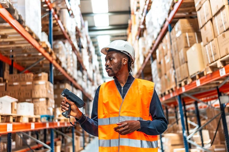 African man scanning parcels doing inventory with wireless scan in a warehouse