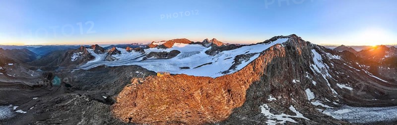 DefaultAtmospheric sunrise in a picturesque mountain landscape, alpenglow, aerial view, mountain hut Becherhaus at the summit Becher and glacier Übeltalferner, Stubai Alps, South Tyrol, Italy, Europe