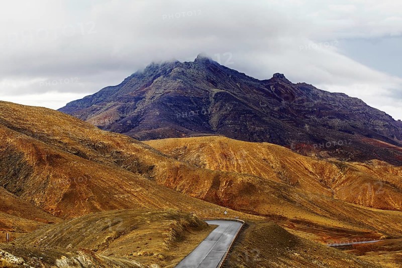 A winding road leads through a mountainous landscape under a cloudy sky, Pajara, Fuerteventura, Canary Islands, Spain, Europe