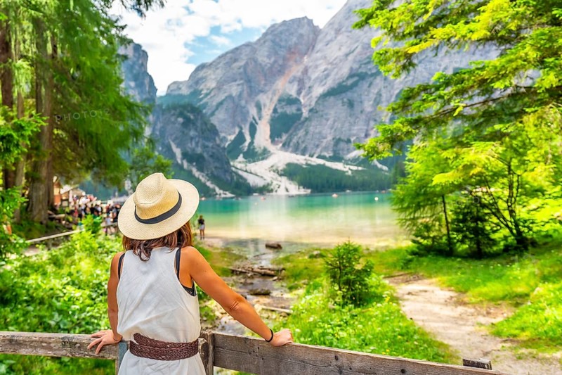 Tourist enjoying breathtaking view of lake braies, surrounded by majestic mountains and lush greenery in the dolomites, italy