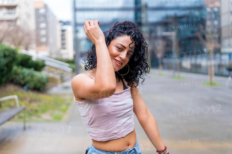 Carefree young woman enjoying music through headphones, dancing in a city park, expressing joy and freedom