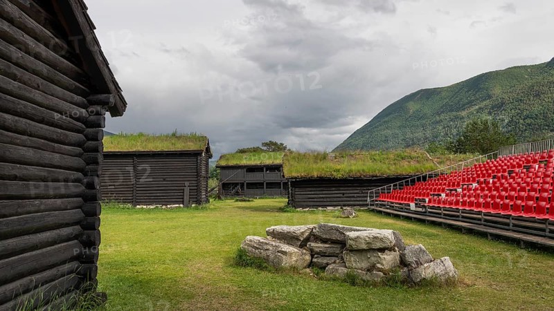 Traditional wooden houses with grass sod roofs, rows of seats with red plastic chairs, ready for an open-air event, backdrop Kristin Lavranstochter film, Jørundgard Middelaldersenter, Olavsweg or Olavsleden, Sel Municipality, Gudbrandsdalen, Norway, Europe