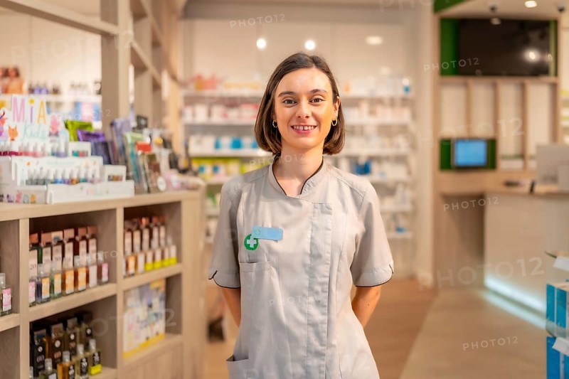 Portrait of a young woman pharmacist standing with hands on back in the store