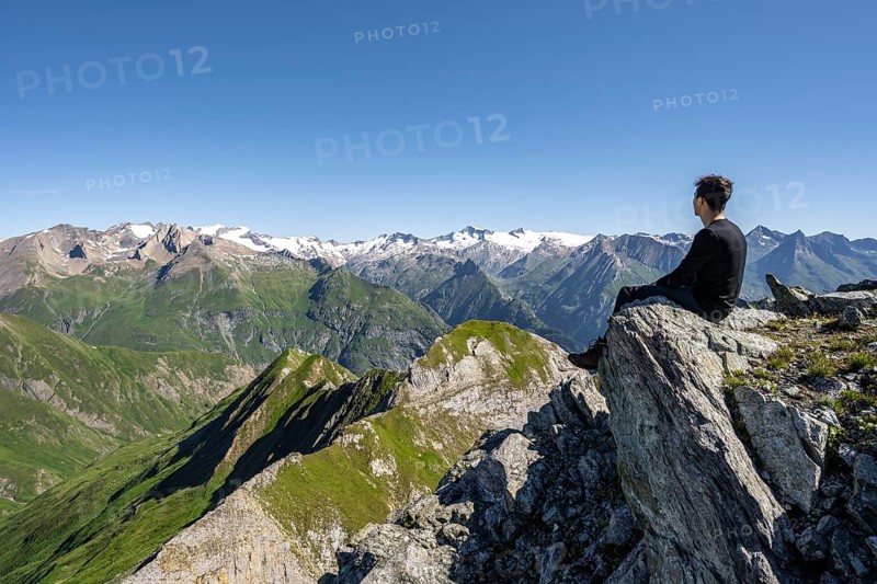 Mountaineer sitting on a rock in front of a mountain panorama with Großvenediger, mountain landscape with mountain peaks of the Venediger group, view from the summit of the Gösleswand, Lasörling group, Hohe Tauern National Park, East Tyrol, Tyrol, Austria, Europe