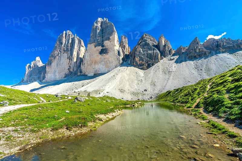Scenic view of tre cime di lavaredo and its reflection in a mountain lake during a sunny summer day in the dolomites