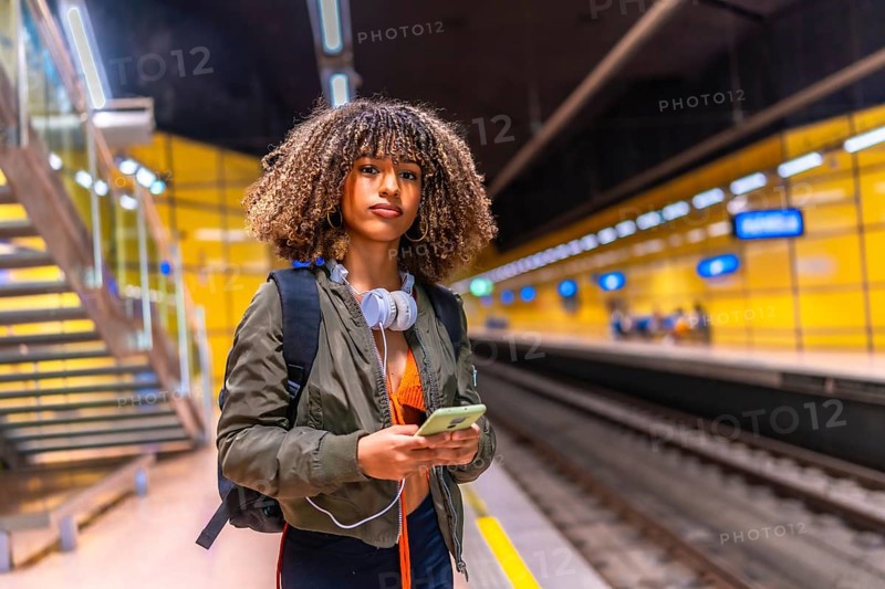 Beauty woman with curly hair and brunette skin using phone while waiting the underground metro