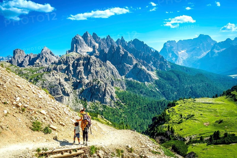 Tourists enjoying breathtaking views while hiking on a scenic trail in tre cime di lavaredo, dolomites, italy, during a sunny summer day