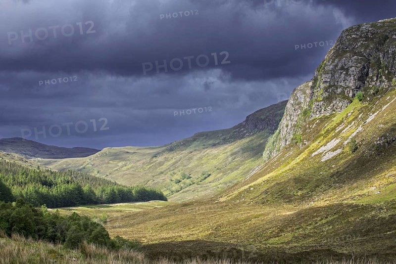 Mountain scenery showing dark rain clouds rolling in over sunny hillside and valley in Wester Ross, Scottish Highlands, Scotland, UK