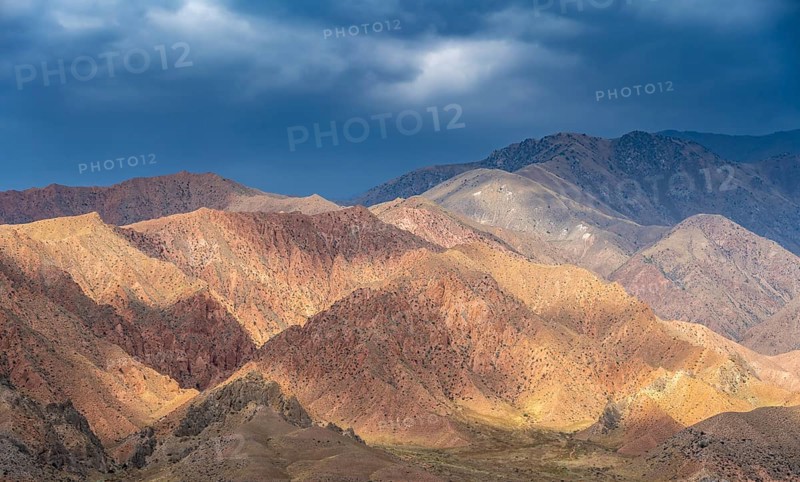 Red and orange mountains in atmospheric light, dramatic cloudy sky, mountain landscape near Kazarman, Naryn region, Kyrgyzstan, Asia