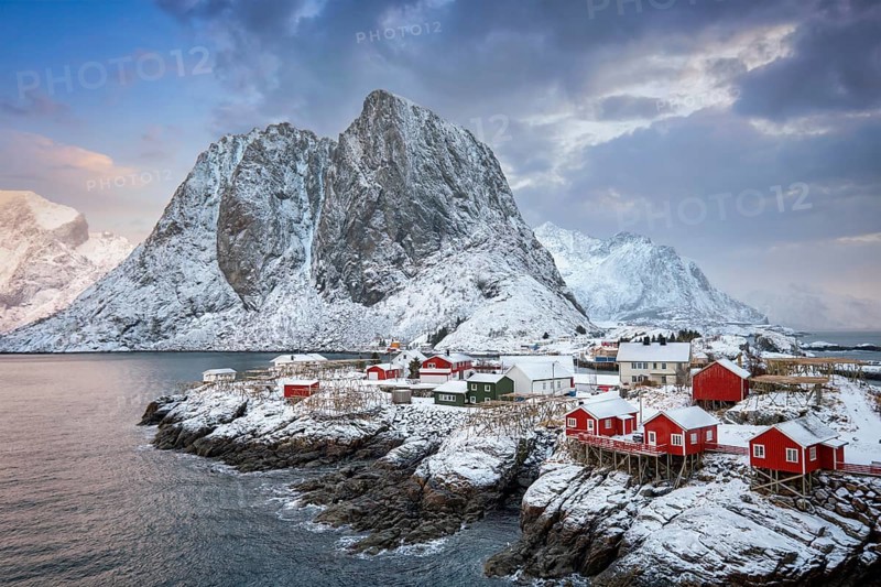 Famous tourist attraction Hamnoy fishing village on Lofoten Islands, Norway with red rorbu houses. With falling snow in winter on sunrise