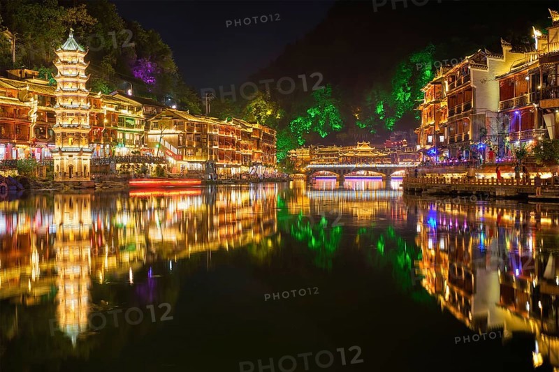 Chinese tourist attraction destination, Feng Huang Ancient Town (Phoenix Ancient Town) on Tuo Jiang River with Wanming Pagoda illuminated at night. Hunan Province, China, Asia