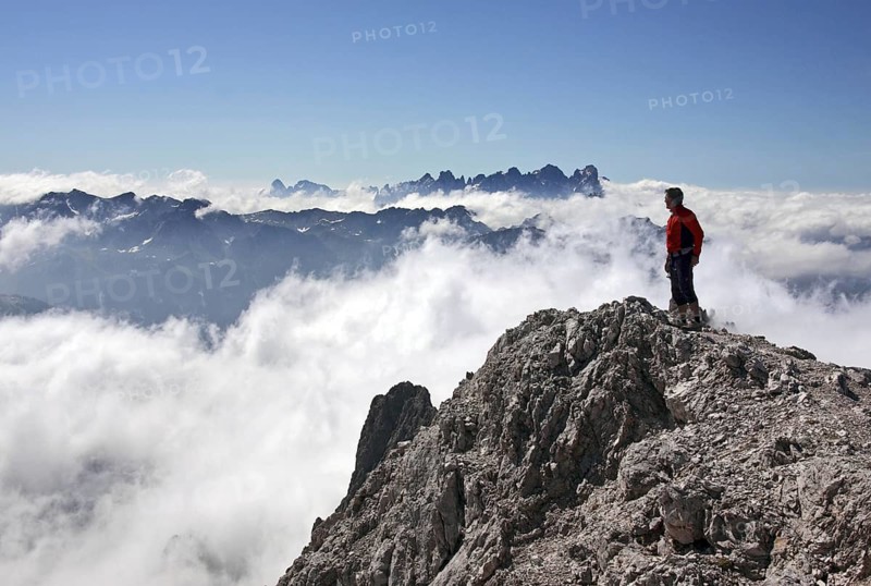 Mountaineer looking from the Cima Scalieret over blanket of clouds and mountain peaks of the Italian Dolomites, Dolomiti di Pala, Catenaccio, Val di Fassa, Italy, Europe