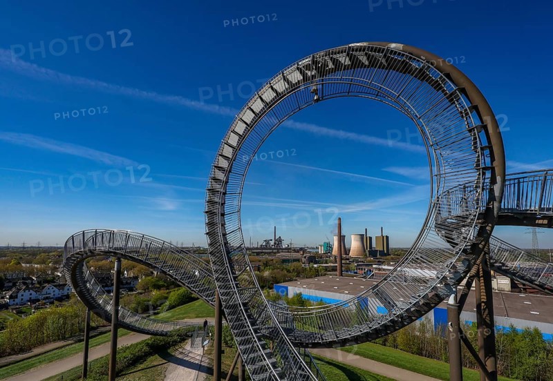 Duisburg, Ruhr area, North Rhine-Westphalia, Germany - Industrial landscape in the Ruhr area, Tiger & Turtle - Magic Mountain in front of HKM steelworks. Tiger and Turtle - Magic Mountain is a large sculpture modelled on a rollercoaster on Heinrich-Hildebrand-Höhe in Angerpark in Duisburg-Angerhausen. The large sculpture is a work of art by Heike Mutter and Ulrich Genth, which was developed as part of the Ruhr.2010 Capital of Culture programme. HKM steelworks, with blast furnaces, Duisburg-Huckingen gas-fired power station on the Rhine. HKM Hüttenwerk Krupp Mannesmann in Duisburg-Hüttenheim. Current shareholdings: 50 % thyssenkrupp Steel Europe AG, 30 % Salzgitter Mannesmann GmbH, 20 % Vallourec Tubes S.A.S. Steel manufacturer Thyssen-Krupp Steel decides to separate from HKM