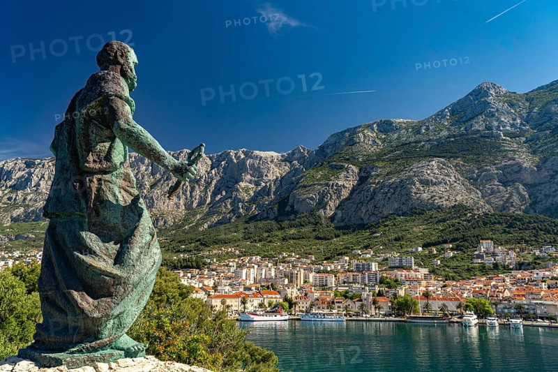 Statue of St Peter in front of the city view of Makarska and the Biokovo Mountains, Croatia, Europe