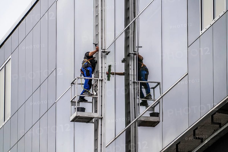 Window cleaner, facade cleaning, window cleaning, on a glass facade in Düsseldorf, ladder cage from the roof