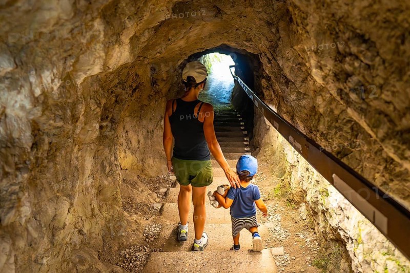 Mother and son walking up the stairs in a tunnel carved into the rock face at tolmin gorge in slovenia